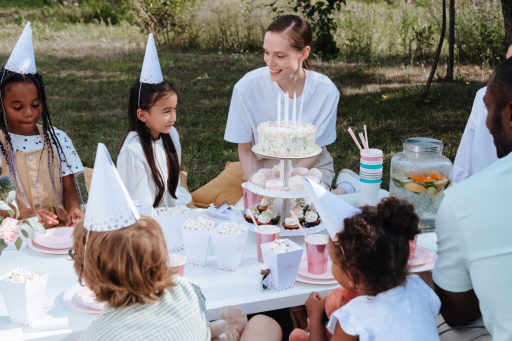Children enjoying a lively outdoor birthday party with cake and decorations.