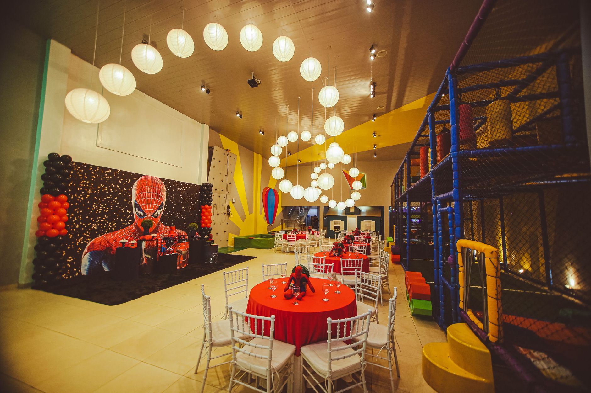Indoor venue decorated with superhero theme for children's party. Bright colors and playful design.